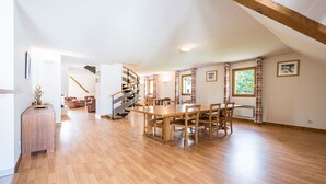 A spacious room with a wooden floor, a dining table with chairs, a spiral staircase, and a window with curtains. - Bright family apartment with balcony (Giez)