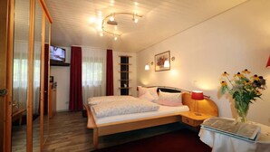 Une chambre à coucher comprenant un lit, une table de chevet, une lampe, un téléviseur et une étagère fixée au mur.