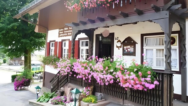 Un bâtiment traditionnel doté d’un balcon orné de fleurs, d’une enseigne et du numéro « 62 » peint sur le mur.