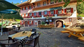 An outdoor seating area with tables and chairs, a building with a sign reading 'Gasthaus zur Linde,' and flower boxes on the windows. - Gasthaus zur Linde – 'Single Room Holzwurm' with Shared Terrace, Garden and Wi-Fi (Oberharmersbach)