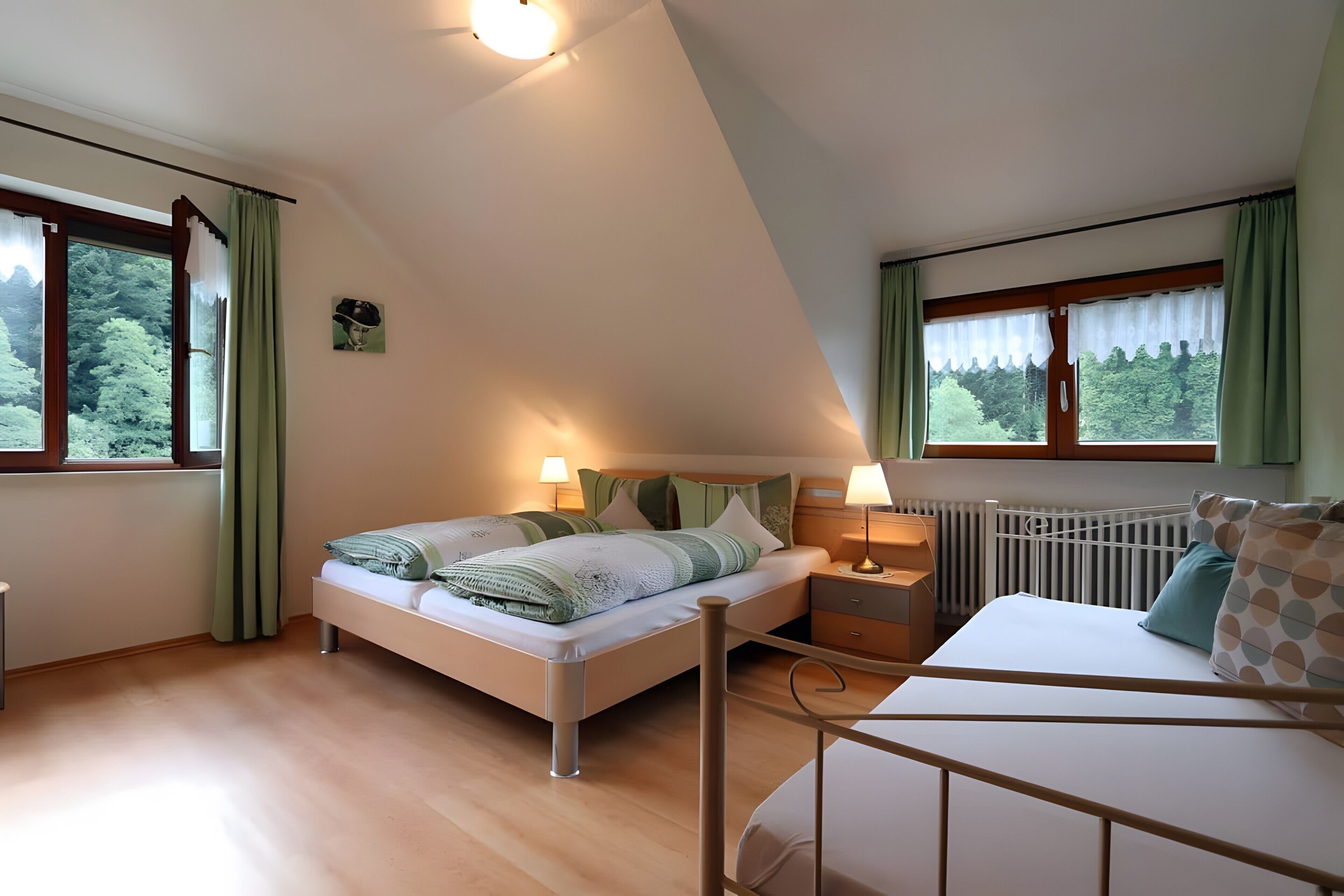 Une chambre à coucher comprenant un lit, des tables de chevet, une commode, une fenêtre avec des rideaux et une vue sur la verdure.