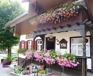 A traditional building with a balcony adorned with flowers, a signboard, and a number '62' on the wall. - Gasthaus zur Linde – Apartment 'Tannenblick' with Shared Terrace, Garden and Wi-Fi (Oberharmersbach)