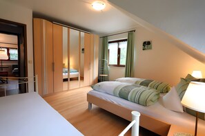 Une chambre à coucher comprenant un lit, une armoire, un bureau et une fenêtre avec des rideaux.
