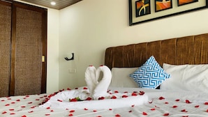 A hotel room with a bed adorned with rose petals and a swan-shaped pillow. - Grand Sea Shades Goa (Canacona)