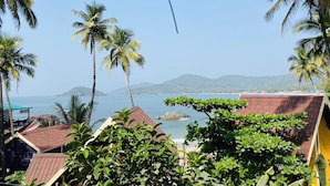 A coastal view with palm trees, a beach, and a mountain in the background. - Grand Sea Shades Goa (Canacona)