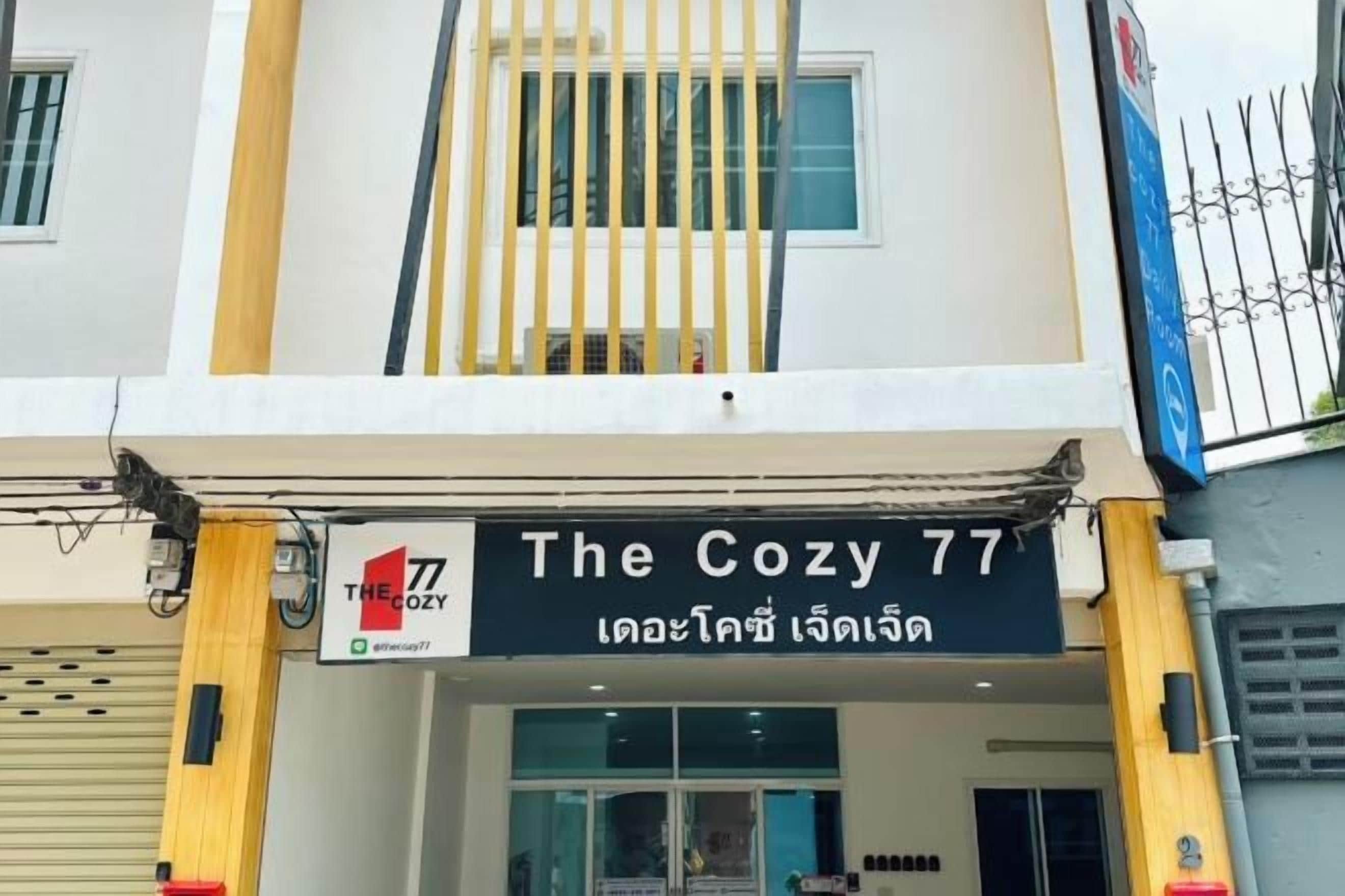 A building with a sign reading 'The Cozy 77' and a Thai phrase below it.