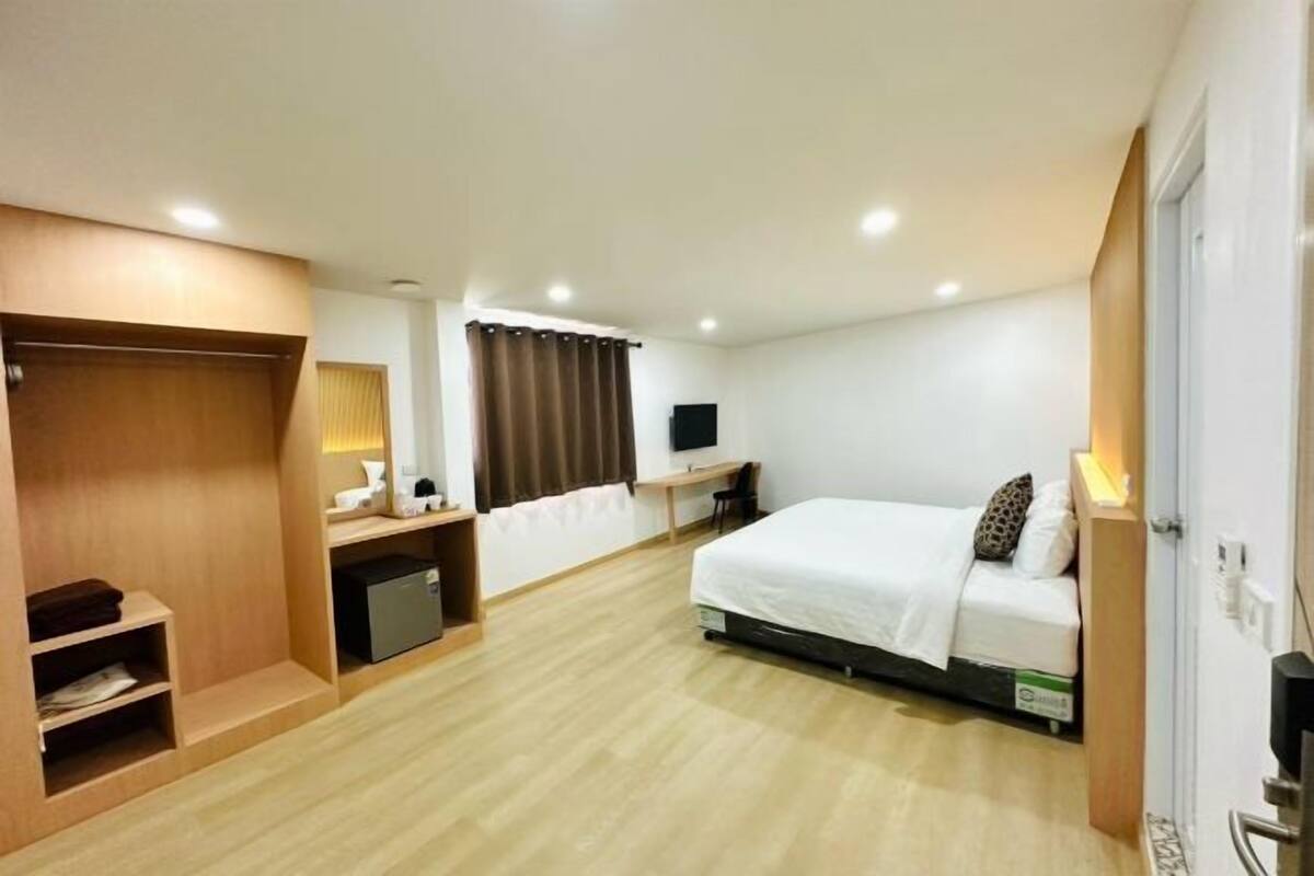 A hotel room with a bed, desk, wardrobe, and a television.