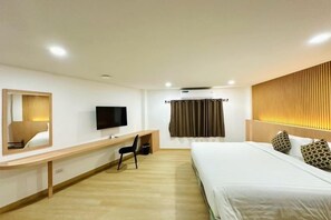 A hotel room with a bed, a desk with a chair, a television, and a window with curtains. - The Cozy77 – No Parking (Bangkok)