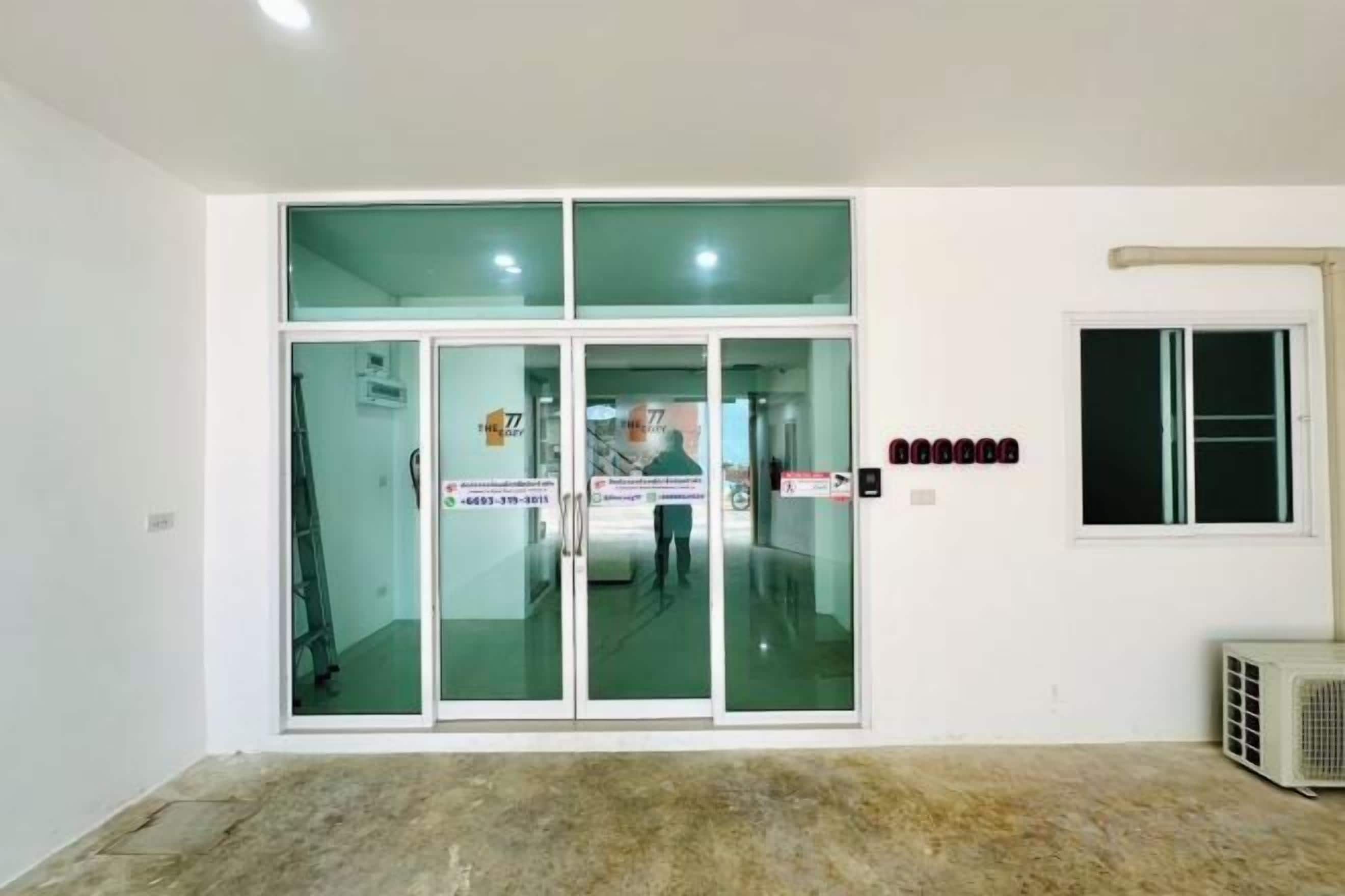 A room with a large glass door, a window, and a wall-mounted air conditioning unit.