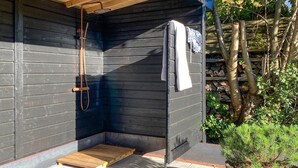 Een houten chalet met een inloopdouche, een houten bankje en een handdoek aan de muur.
