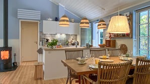 Een moderne keuken met een centraal eiland, een houten eettafel en hangende pendelverlichting.