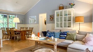 Een gezellige woonkamer met een eethoek, houten meubels en een kast met glazen deuren.