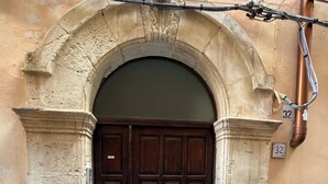 A dark wooden door with a stone archway, a small step leading up to it, and a number '32' on the wall to the right. - A stone's throw from the cathedral: authentic Sicilian house in Ortigia (Siracusa)