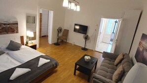 Una habitación de hotel con cama, sofá, televisión y ventilador.