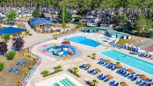 An aerial view of a resort with a water park, multiple swimming pools, and sun loungers.