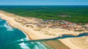 An aerial view of a coastal town with a beach, houses, and greenery.