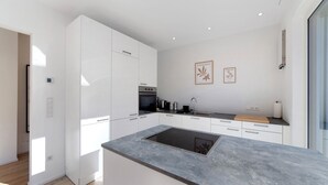 A modern kitchen with white cabinetry, a built-in stove, and a grey countertop. - Apartment 'Naturns Mountain Suite' with Mountain View, Private Terrace and Wi-Fi (Naturno Naturns BZ)