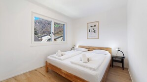 A bedroom with a wooden bed, white linens, a nightstand, a lamp, and a framed picture on the wall. - Apartment 'Naturns Mountain Suite' with Mountain View, Private Terrace and Wi-Fi (Naturno Naturns BZ)