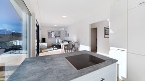 A modern kitchen with a built-in stove, white cabinetry, and a dining area with a table and chairs. - Apartment 'Naturns Mountain Suite' with Mountain View, Private Terrace and Wi-Fi (Naturno Naturns BZ)