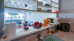 Una cocina con encimera blanca, un lavamanos, un microondas y una ventana con vistas al exterior.