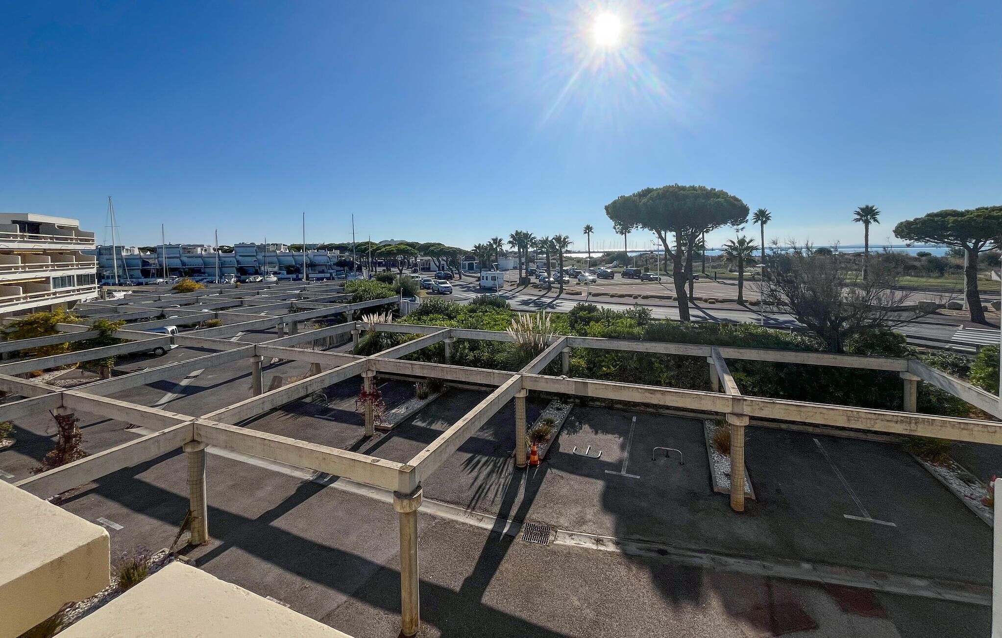 A parking area with multiple levels and a clear view of the surrounding landscape, including trees and a distant body of water.