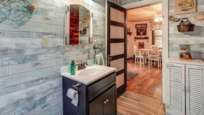Un baño rústico con pared de madera, un lavabo y un espejo.