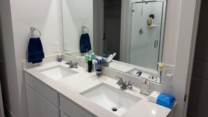 Ein Badezimmer mit zwei Waschbecken, einem großen Spiegel und einer Duschkabine.