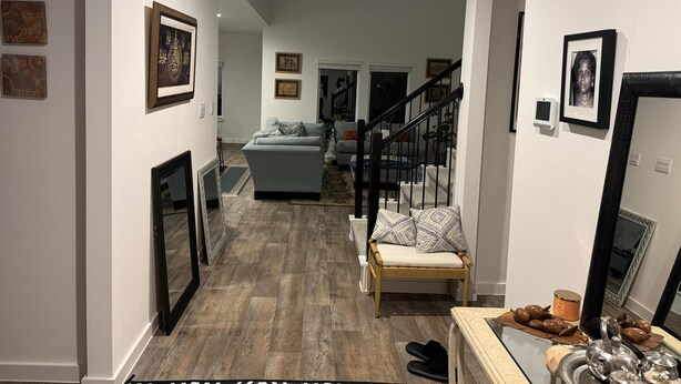 Ein modernes Wohnzimmer mit einer grauen Couch, einer Holzbank und einer Treppe zu einer weiteren Ebene.