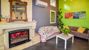 A living room with a fireplace, a sofa, a coffee table, and a green wall with artwork.