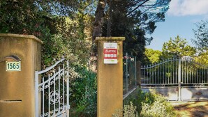 A gated entrance with a metal gate, a sign indicating an alarm system, and a house number 1565.
