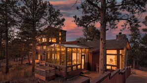 A rustic cabin with a glass-enclosed porch, surrounded by trees.