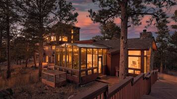A rustic cabin with a glass-enclosed porch, surrounded by trees.