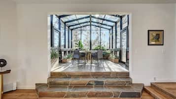 Een modern interieur met een stenen trap die leidt naar een glazen patio met buitenmeubilair en planten.