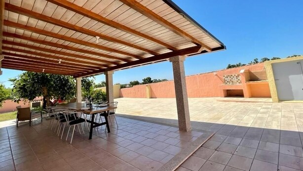 A covered patio area with a tiled floor and a wooden pergola.