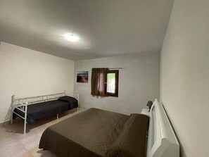 Una habitación con una cama individual, una mesita y una ventana con cortinas.