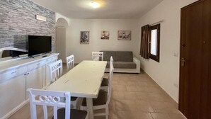 A compact living space with a dining area, a sofa, a television, and a kitchen counter.