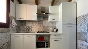 A compact kitchen with white cabinets, a built-in microwave, a red toaster, and a gas stove.