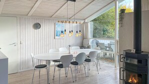 A modern dining area with a round table, six chairs, a built-in stove, and a large window overlooking a deck. - Pet friendly home in Humble with sauna (Humble)