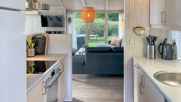 A modern kitchen with a built-in oven, a TV, and a dining area with a sofa and table. - Pet friendly home in Humble with sauna (Humble)