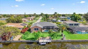 Een woongebied met huizen, een zwembad en een steiger aan het water.