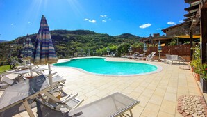 A swimming pool with lounge chairs and umbrellas, surrounded by a wooden fence and a mountain backdrop. - Awesome home in Cicerale (Cicerale)