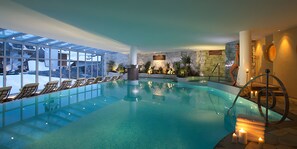 An indoor swimming pool with glass walls, lounge chairs, and a stone wall with plants. - Apartment 'Residenz Nussbaumer Apt A' with Mountain View, Shared Pool and Wi-Fi (Siusi alle Sciliar)