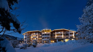 Un hotel de varios pisos con balcones, rodeado de árboles cubiertos de nieve.