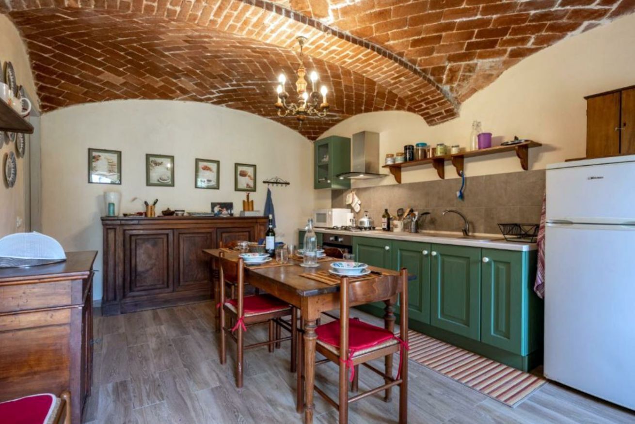 Una cocina con techo de ladrillo, armarios de madera y una mesa de comedor con sillas.
