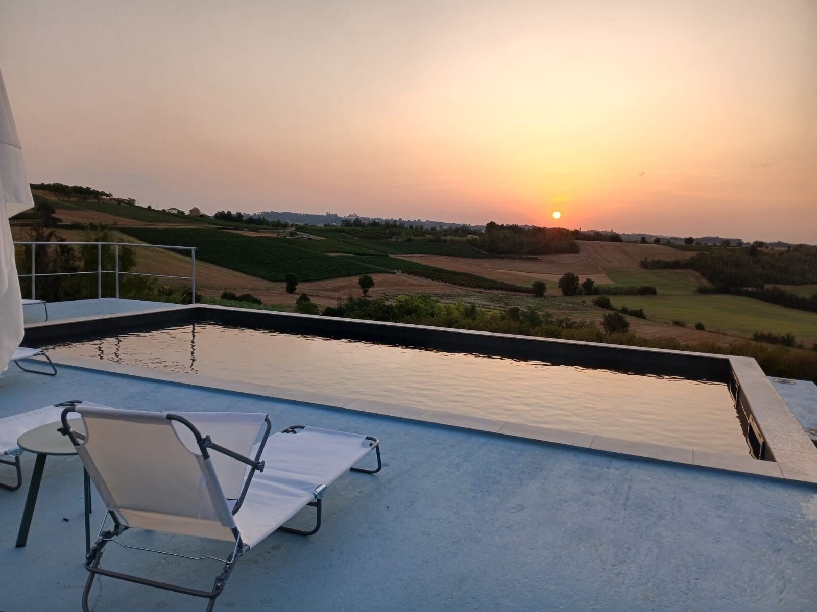 Una piscina exterior amb vistes a un paisatge amb turons al capvespre.