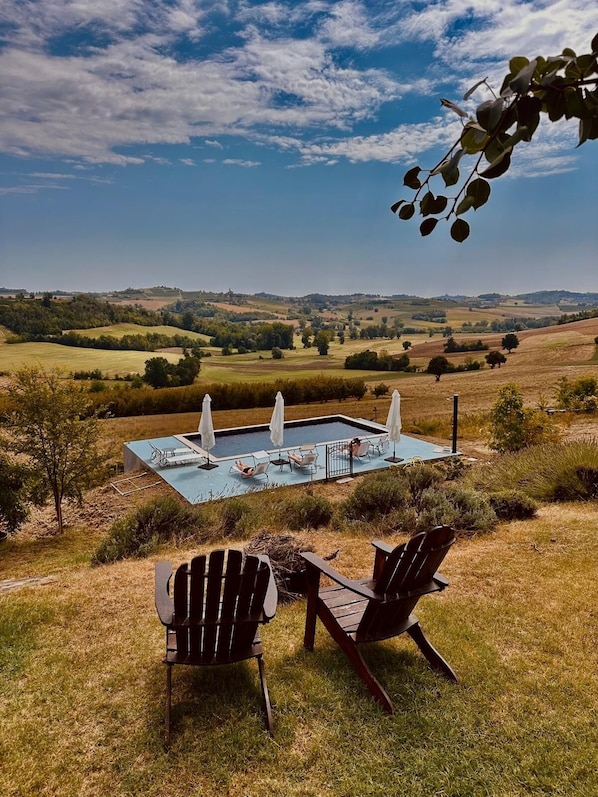 Zona de piscina con sillas de descanso y vistas a colinas onduladas.