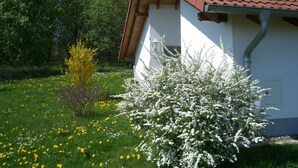 Un edificio con techo de tejas rojas, paredes blancas y un jardín con flores amarillas y blancas.