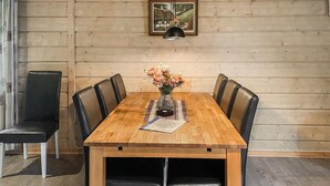 Una mesa de comedor de madera con seis sillas de cuero negro, un jarrón con flores y un cuadro en la pared.