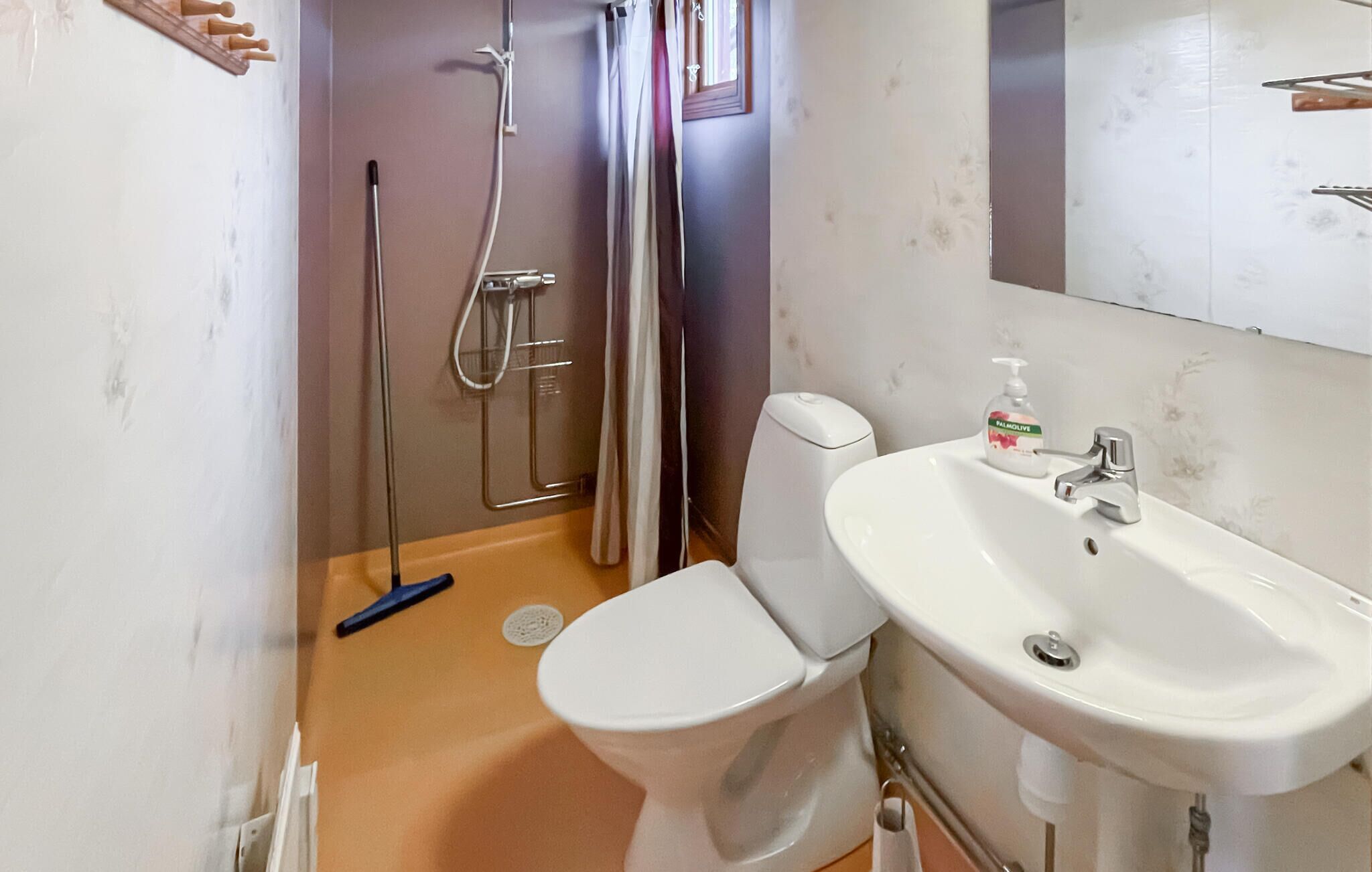 A bathroom with a toilet, sink, shower, and a towel rack.