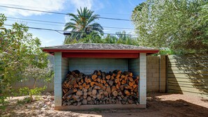 Ein kleines Gebäude mit rotem Dach und einem Holzstapel darin.